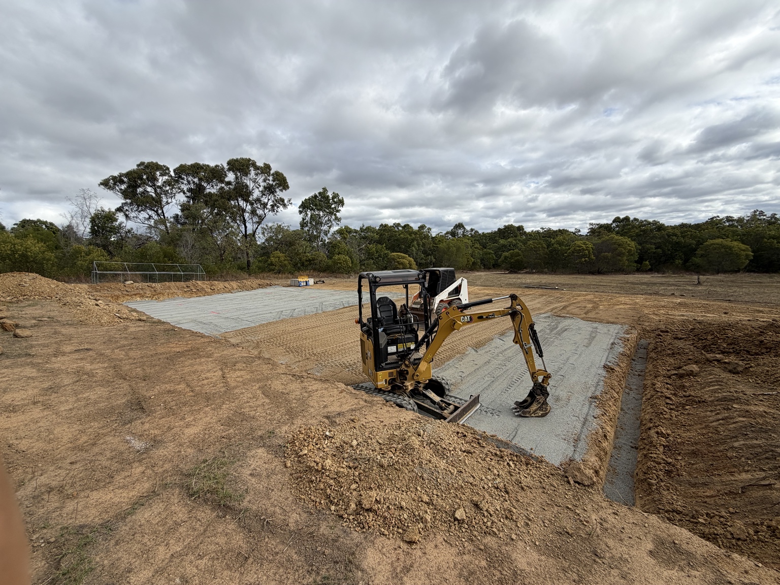 Mini excavator completing earthworks around a concrete pad