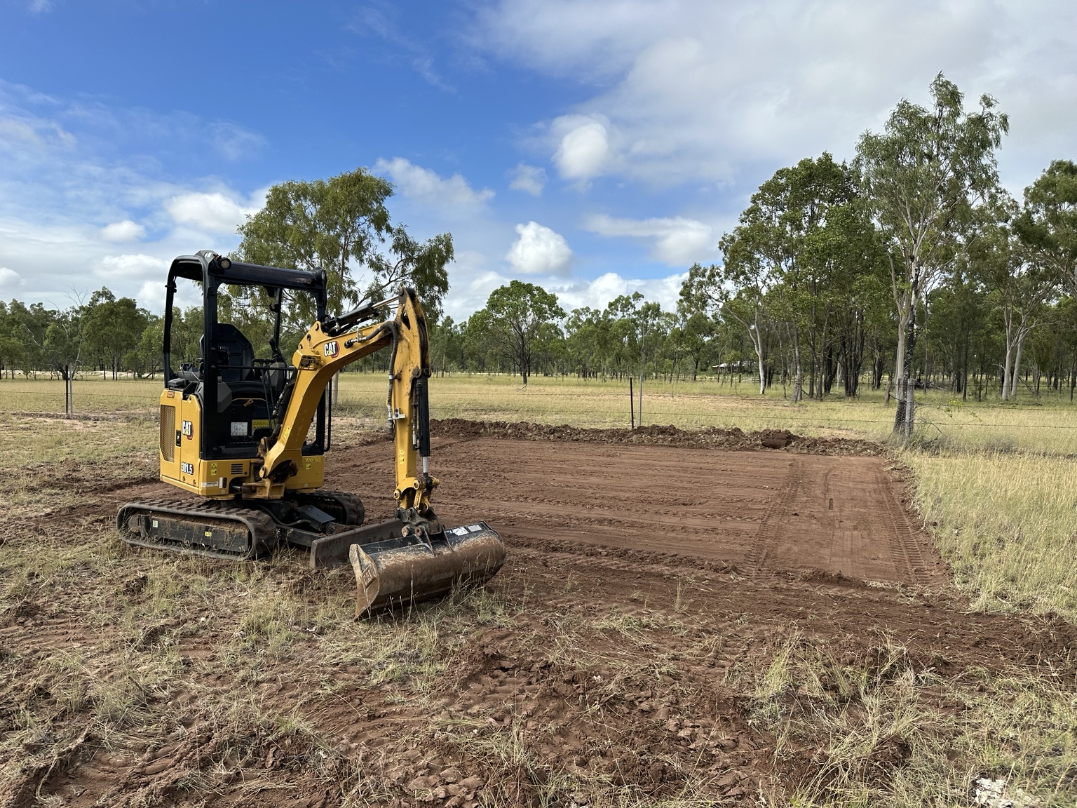 Mini excavator levelling ground on a rural property